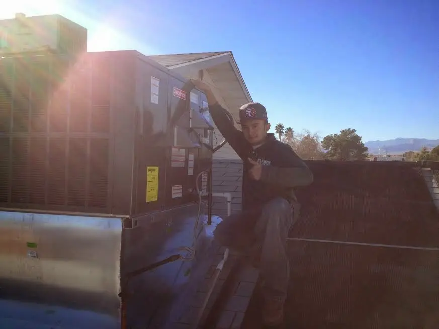 HVAC technician performing AC Tune-Up on a rooftop unit in Chino